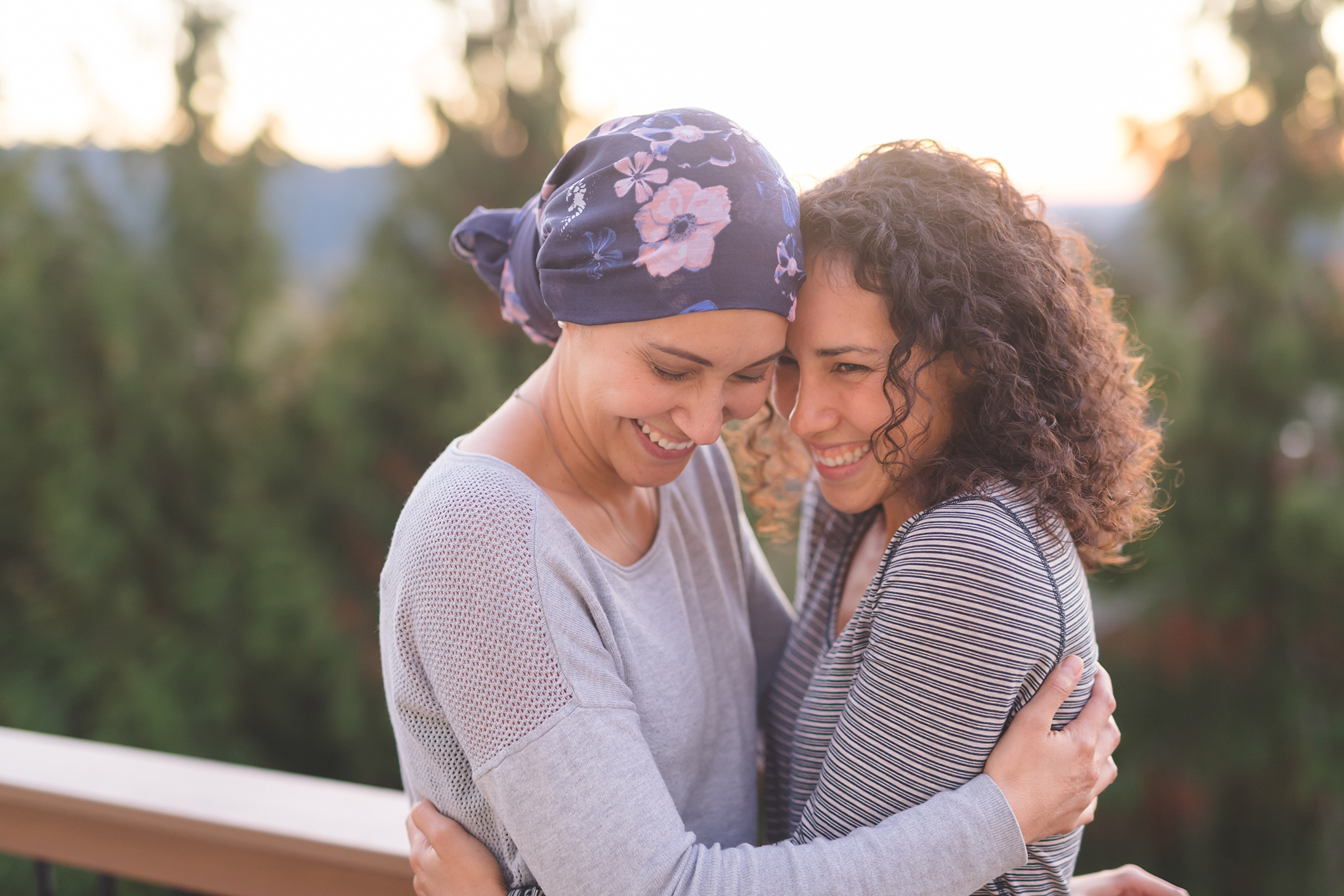 Woman cancer patient with scarf hugging another woman